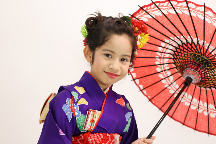 唐傘を回しながら、すこし気取ってお着物でポーズする7歳の女の子。七五三が嬉しいという表情。