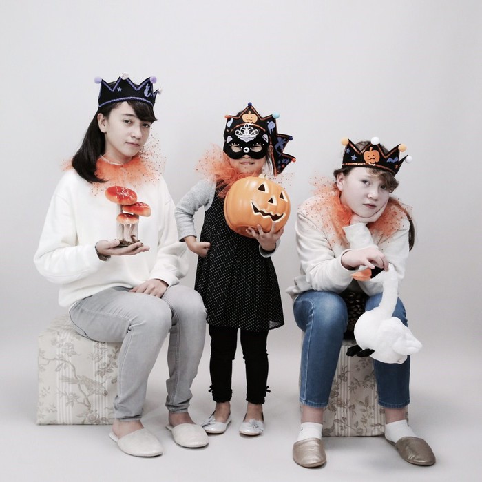 シュールなハロウィーンの仮装写真。かぼちゃと一緒に3人の女の子たち。